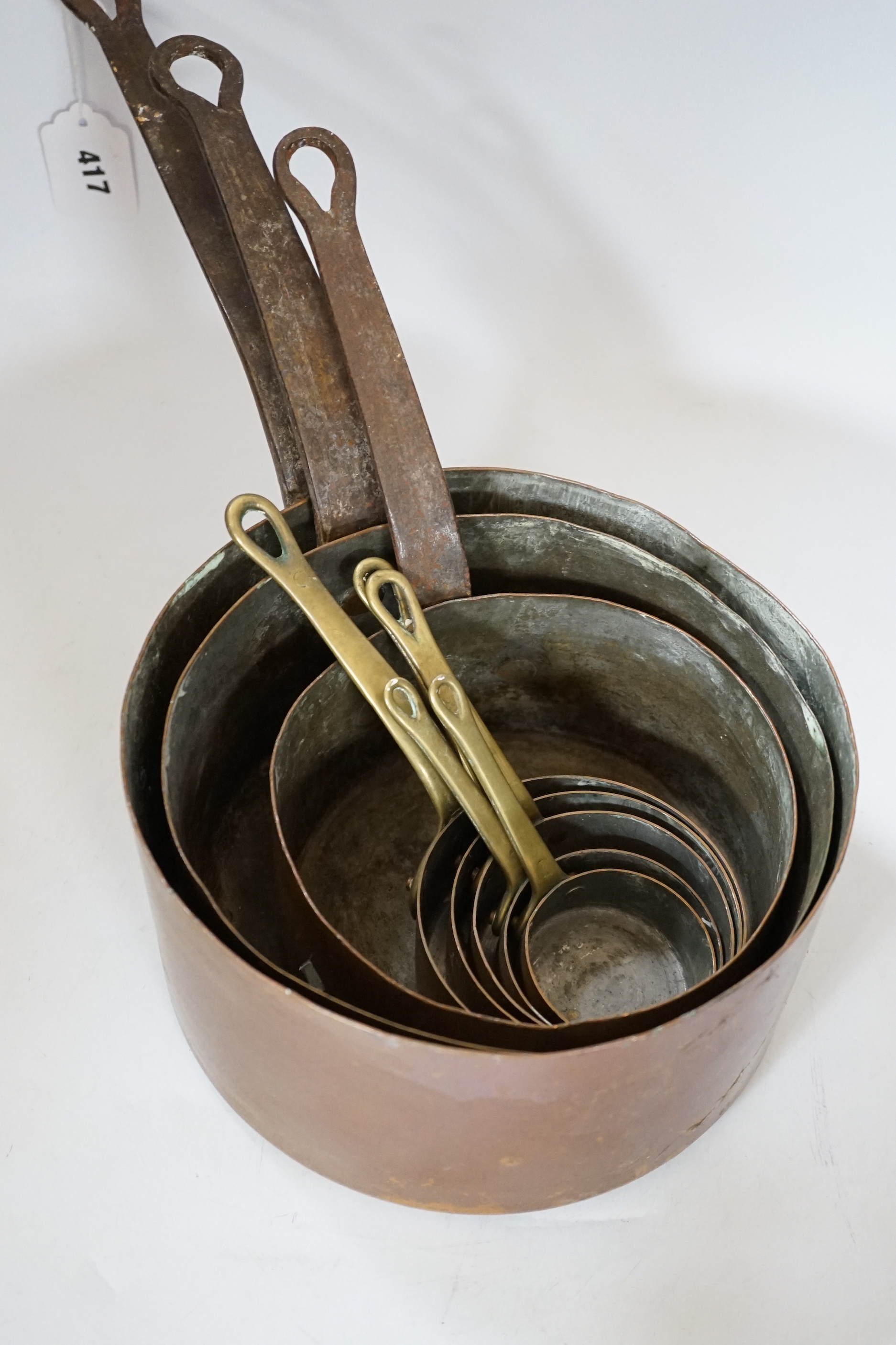 A copper two handled jam pan and a graduated set of eight copper saucepans